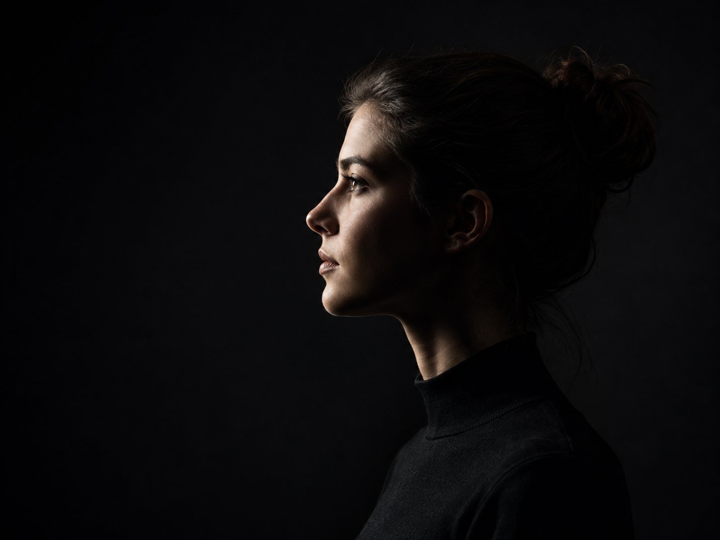 Studioporträt einer Person im Profil vor dunklem Hintergrund